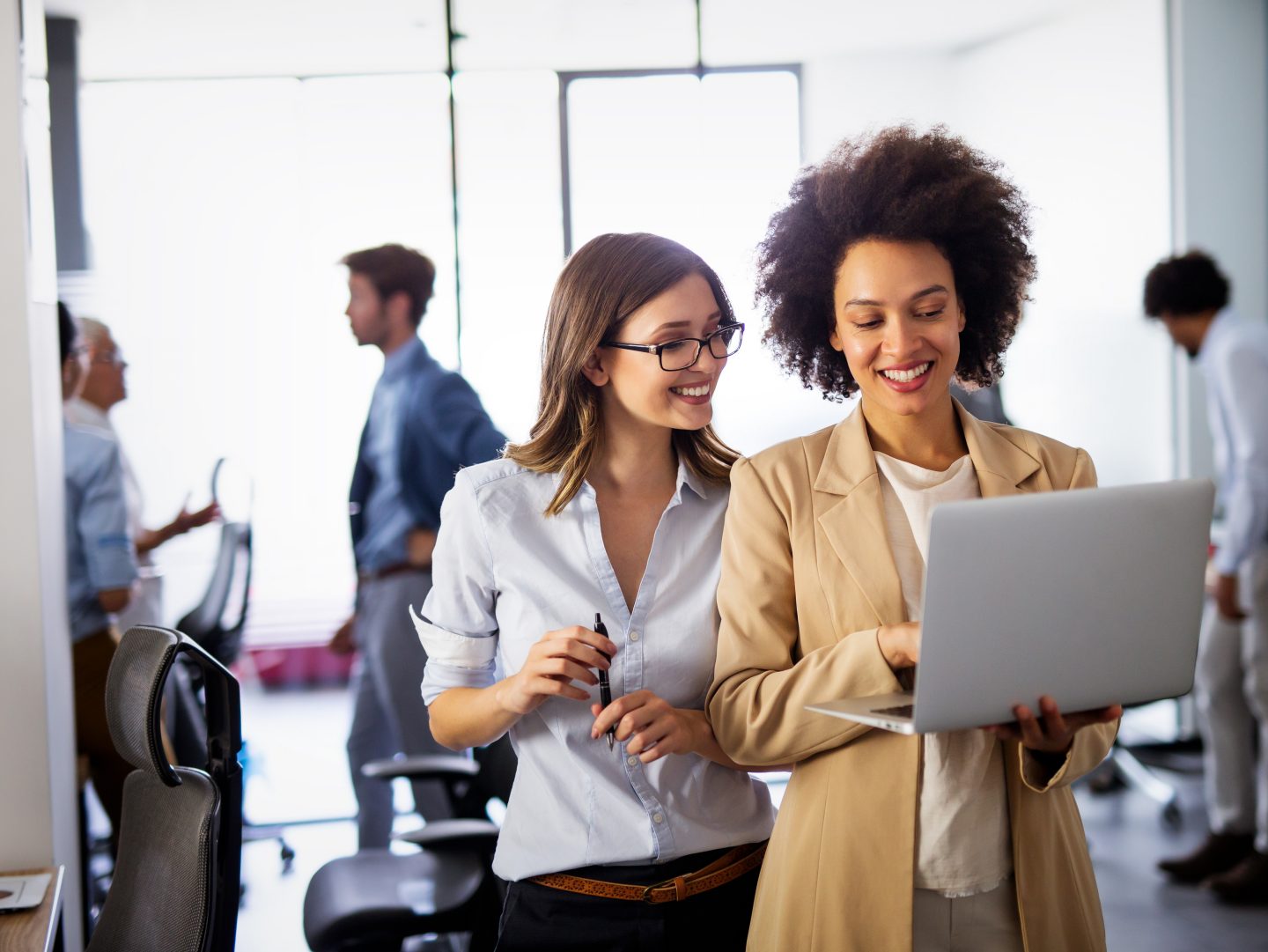 Happy multiethnic success business women working together online on a laptop in corporate office.