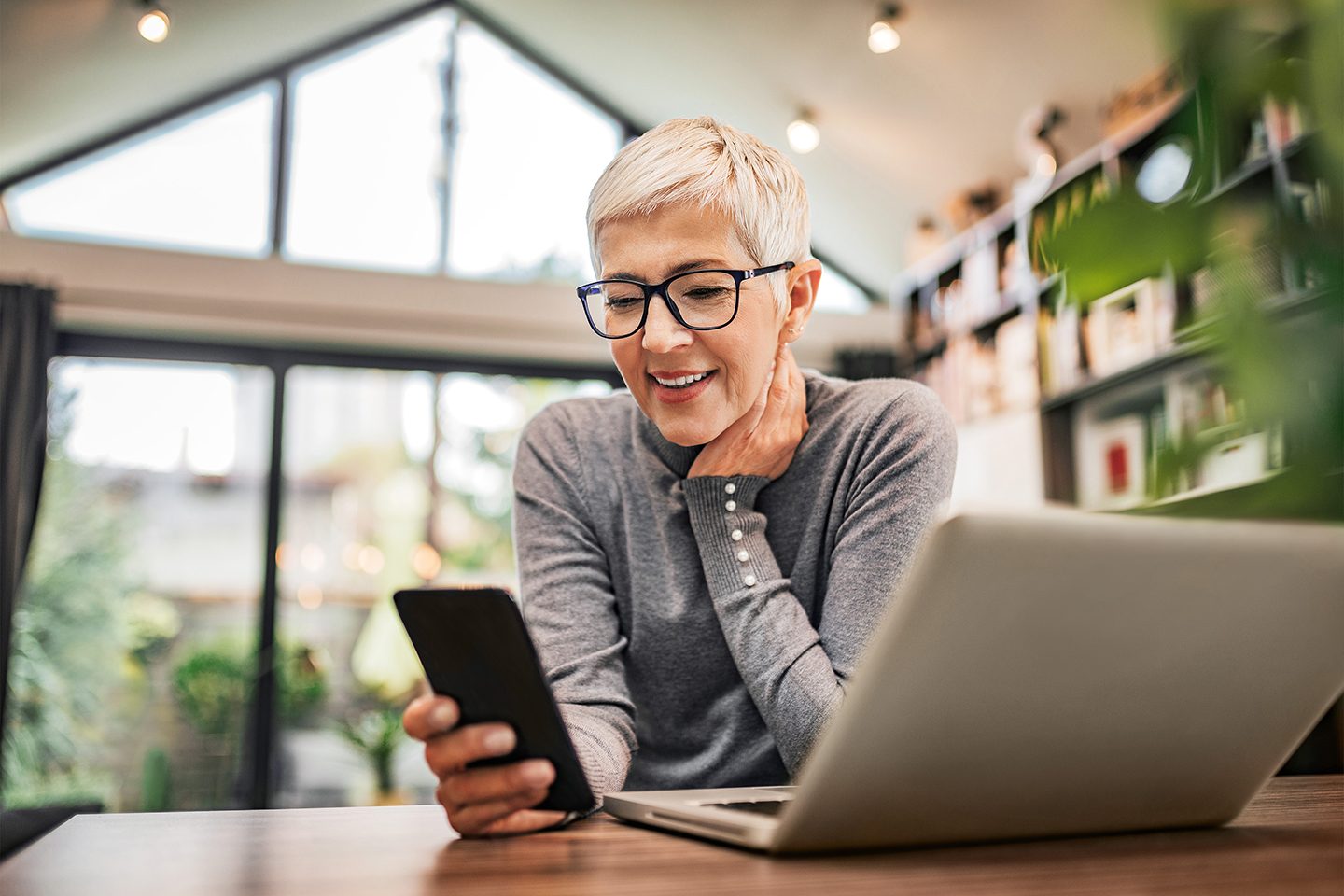 Portrait of a cheerful senior businesswoman using smart phone at home office, close-up.